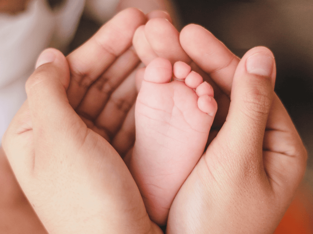 La réflexologie, mains féminines entourant le pied d'un bébé